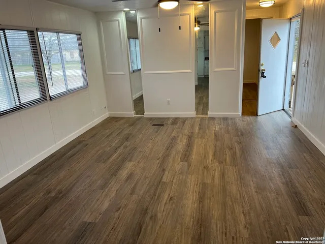 a view of an empty room with wooden floor and a window