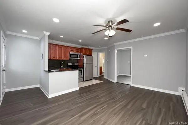 a view of an empty room with kitchen window a ceiling fan and wooden floor
