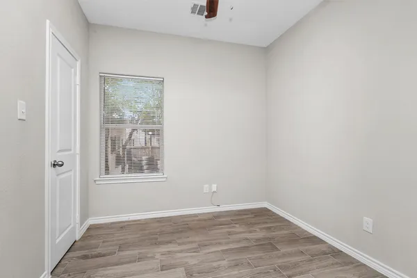 a view of an empty room with wooden floor and a window