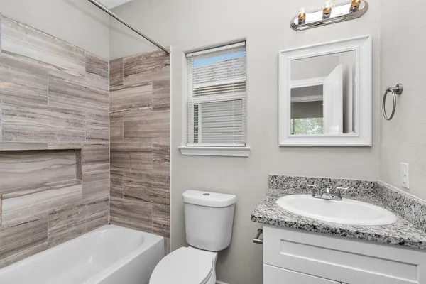 a bathroom with a granite countertop sink toilet and bathtub