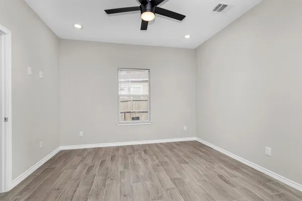 an empty room with wooden floor fan and windows