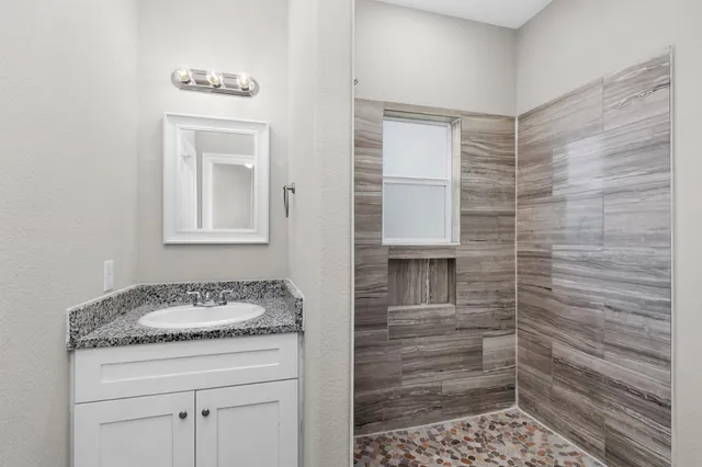 a bathroom with a granite countertop sink a vanity and a shower