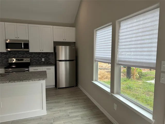 a kitchen with stainless steel appliances granite countertop a refrigerator a stove a sink and a microwave