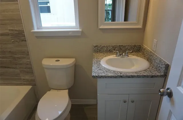 a bathroom with a granite countertop toilet sink and mirror