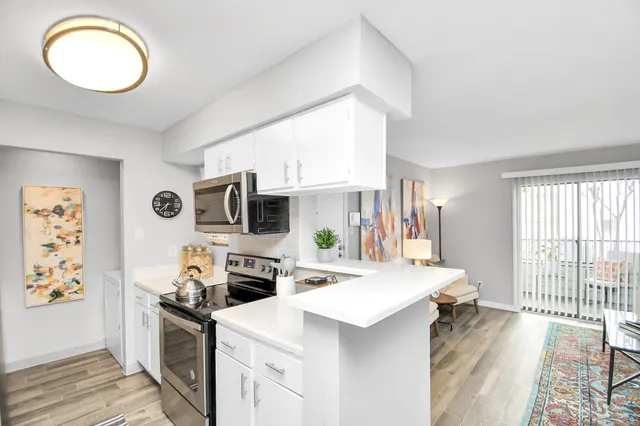 a kitchen with stainless steel appliances a stove a sink a microwave a refrigerator and cabinets