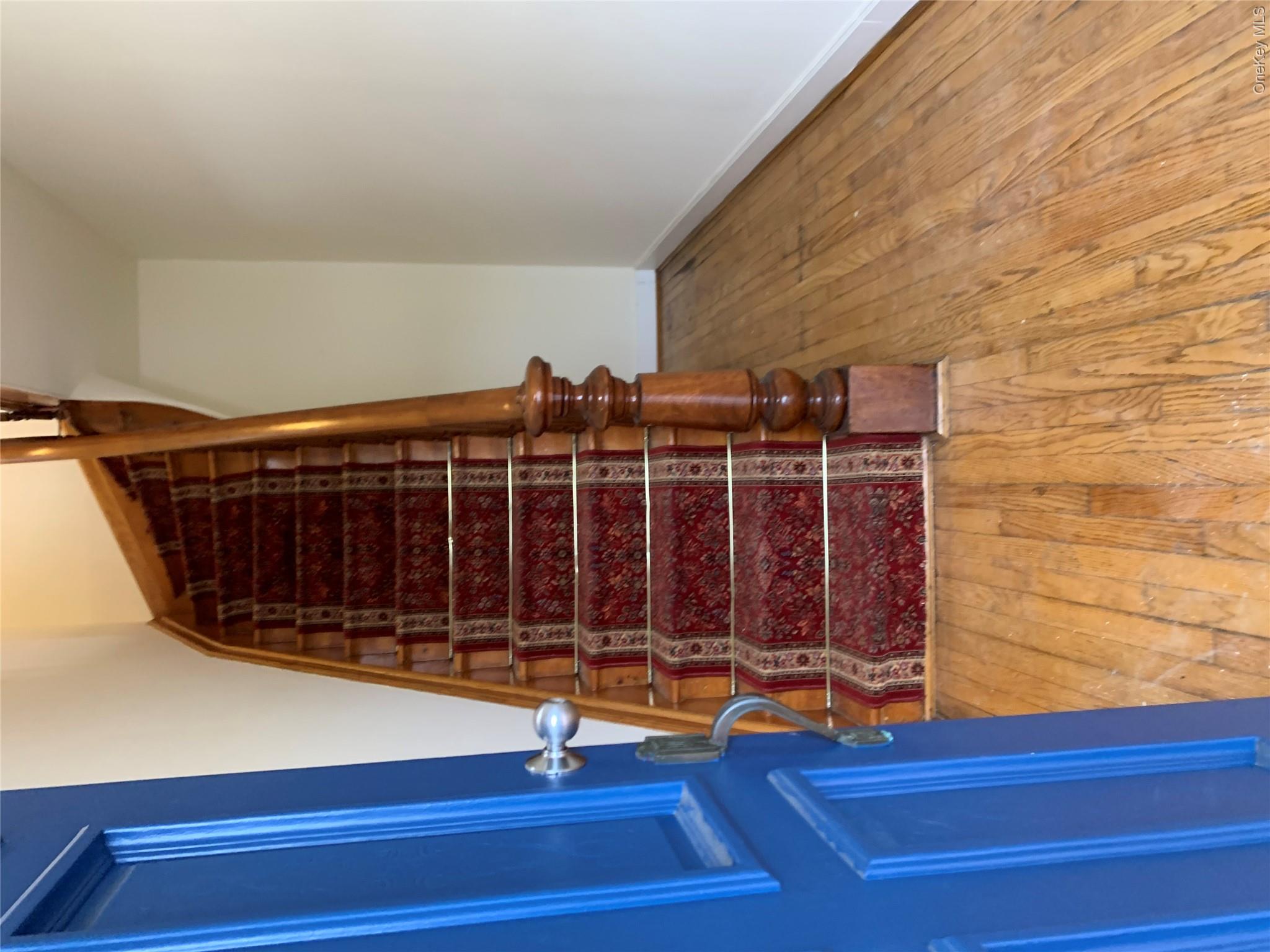 7 Clinton Street Haverstraw, NY 10927 - Photo 3 of 20 Hardwood flooring throughout the entry, complemented by a traditional wood staircase featuring a patterned runner and decorative newel post