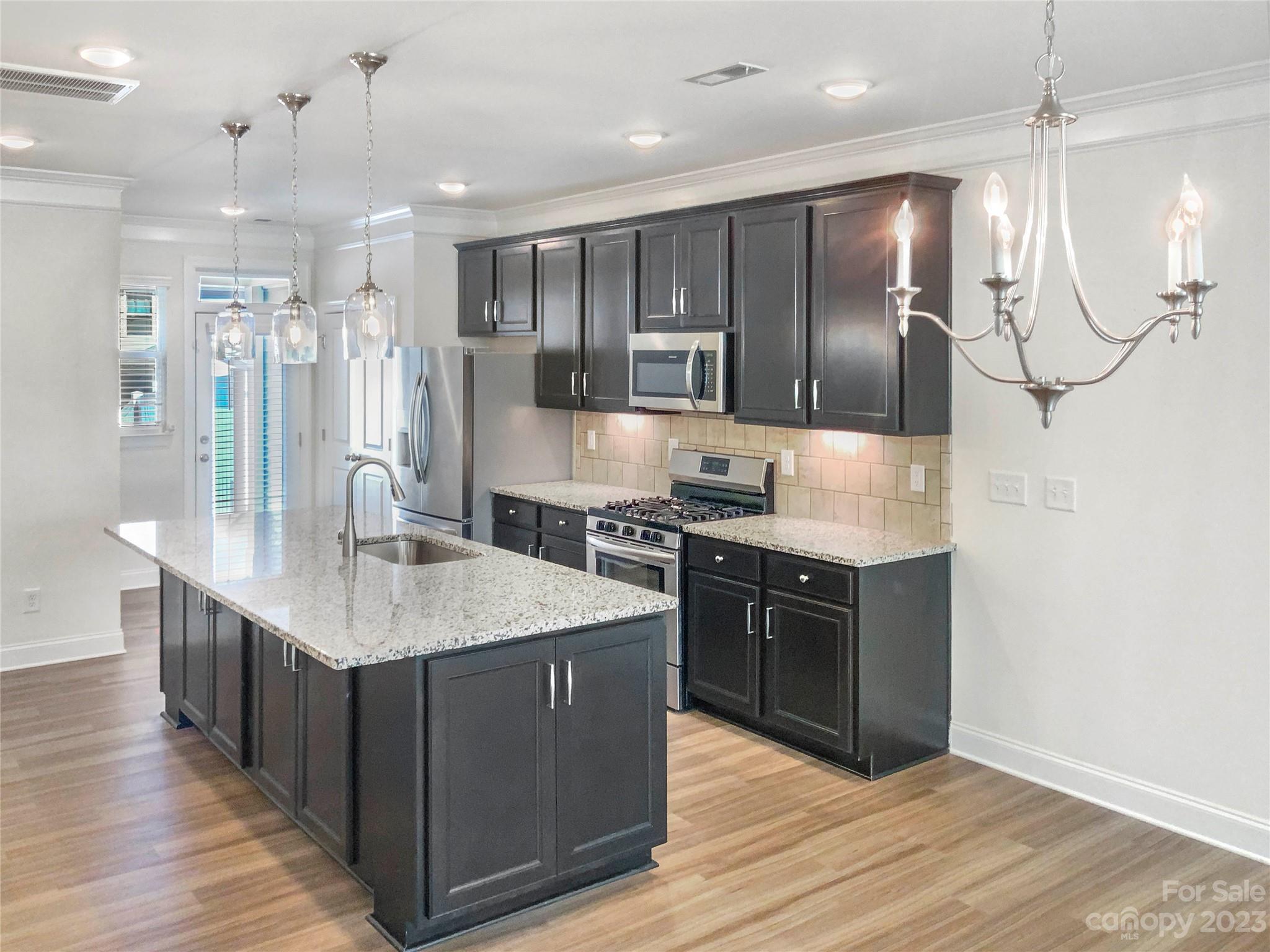 208 Waterlynn Ridge Road, Unit B Mooresville, NC 28117 - Photo 7 of 21 a large kitchen with a center island wooden floor stainless steel appliances and living room view