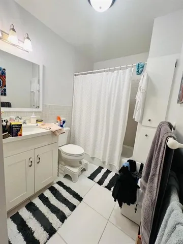 a living room with a black white checkered floor furniture a rug and a window