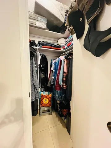 a view of walk in closet with clothes and shoes