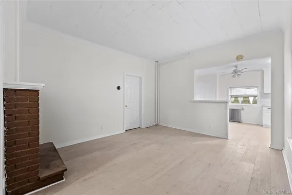 a view of kitchen and empty room with wooden floor