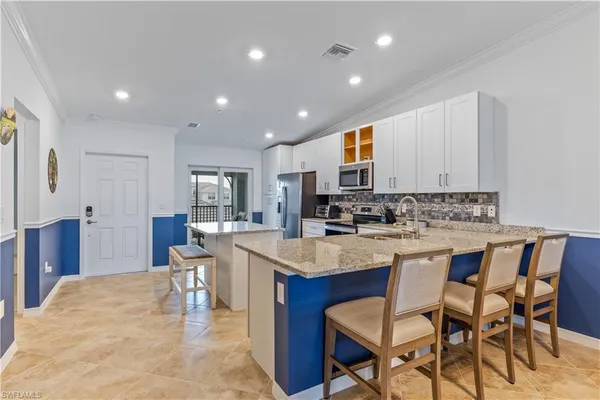 a kitchen with stainless steel appliances granite countertop a table chairs sink refrigerator and cabinets