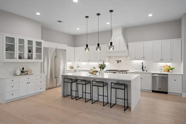 a large kitchen with stainless steel appliances kitchen island granite countertop a refrigerator and a stove top oven