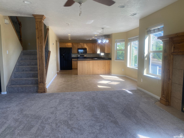 83 Canterbury Circle Logan, UT 84321 - Photo 23 of 23 Kitchen with open floor plan, black appliances, dark countertops, light carpet, and a ceiling fan
