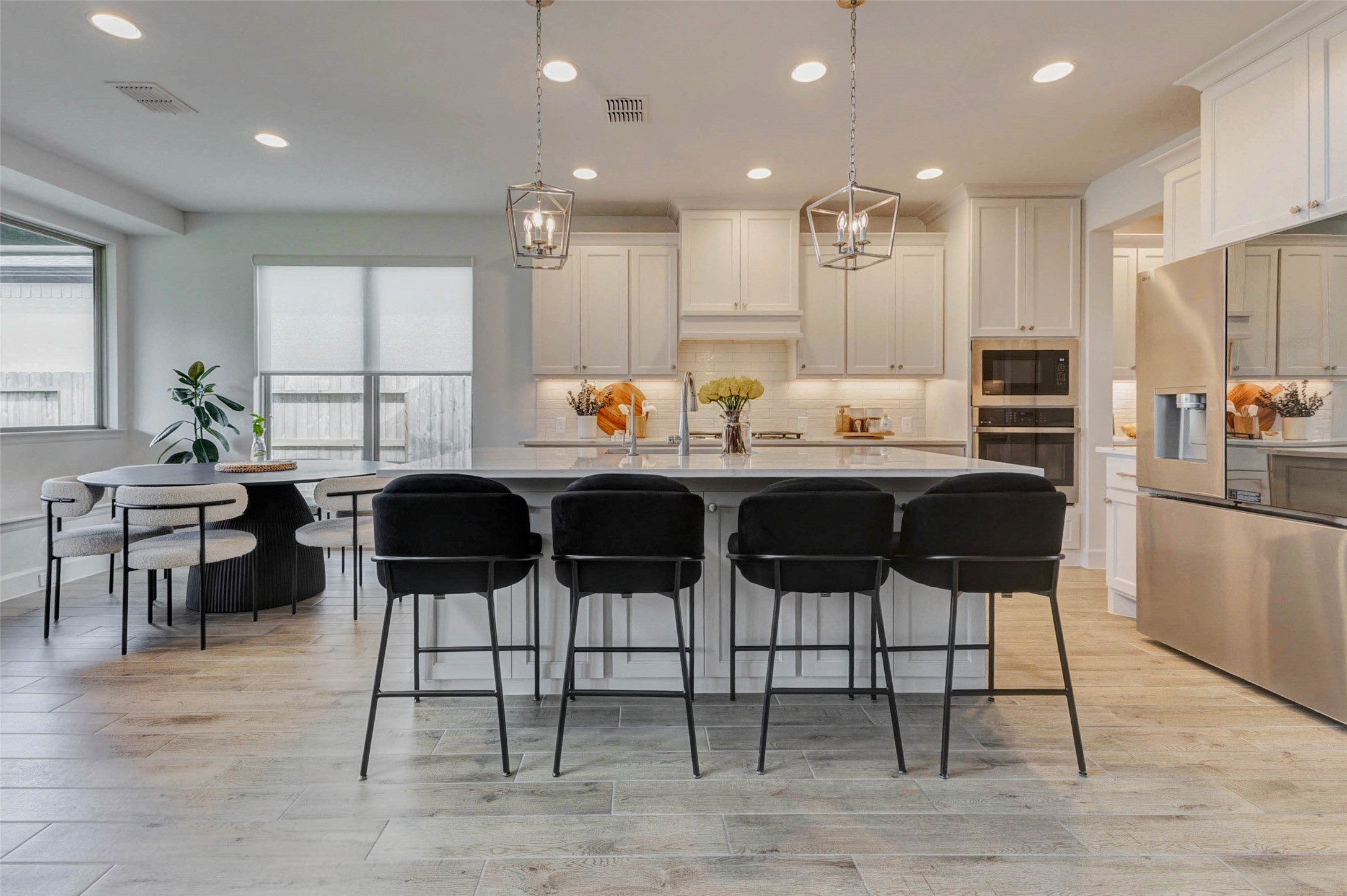 a kitchen with stainless steel appliances kitchen island granite countertop a dining table chairs refrigerator and sink