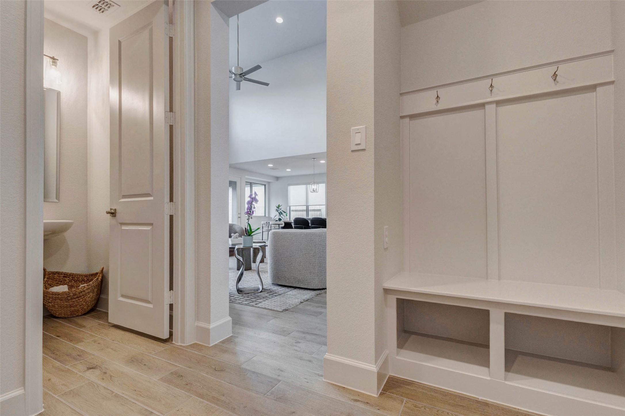 4322 Southpoint Way Fulshear, TX 77441 - Photo 26 of 50 Modern, bright entryway with a built-in bench and hooks for organization. It leads to an open living area with a cozy seating arrangement and a ceiling fan, offering a welcoming and functional space.