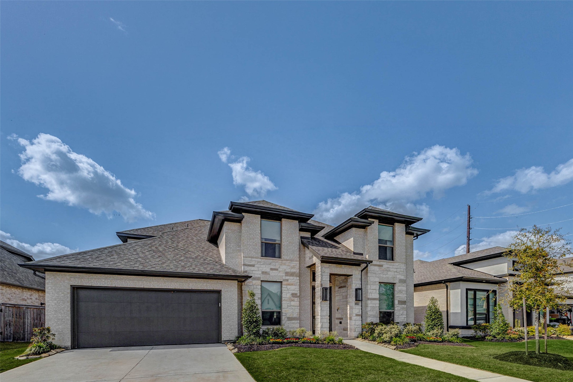 4322 Southpoint Way Fulshear, TX 77441 - Photo 3 of 50 Modern two-story home with a stone facade and dark trim, featuring a double garage and landscaped front yard.