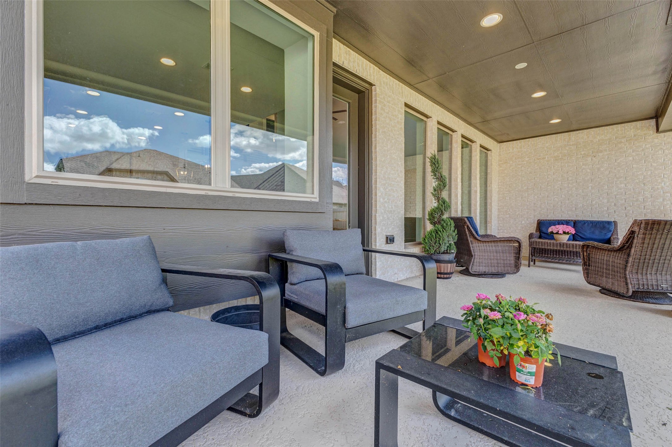 4322 Southpoint Way Fulshear, TX 77441 - Photo 48 of 50 Spacious, covered patio featuring comfortable seating, a coffee table with plants, and stylish wicker furniture. The area is well-lit with recessed lighting and offers a relaxing outdoor space ideal for entertaining or unwinding.