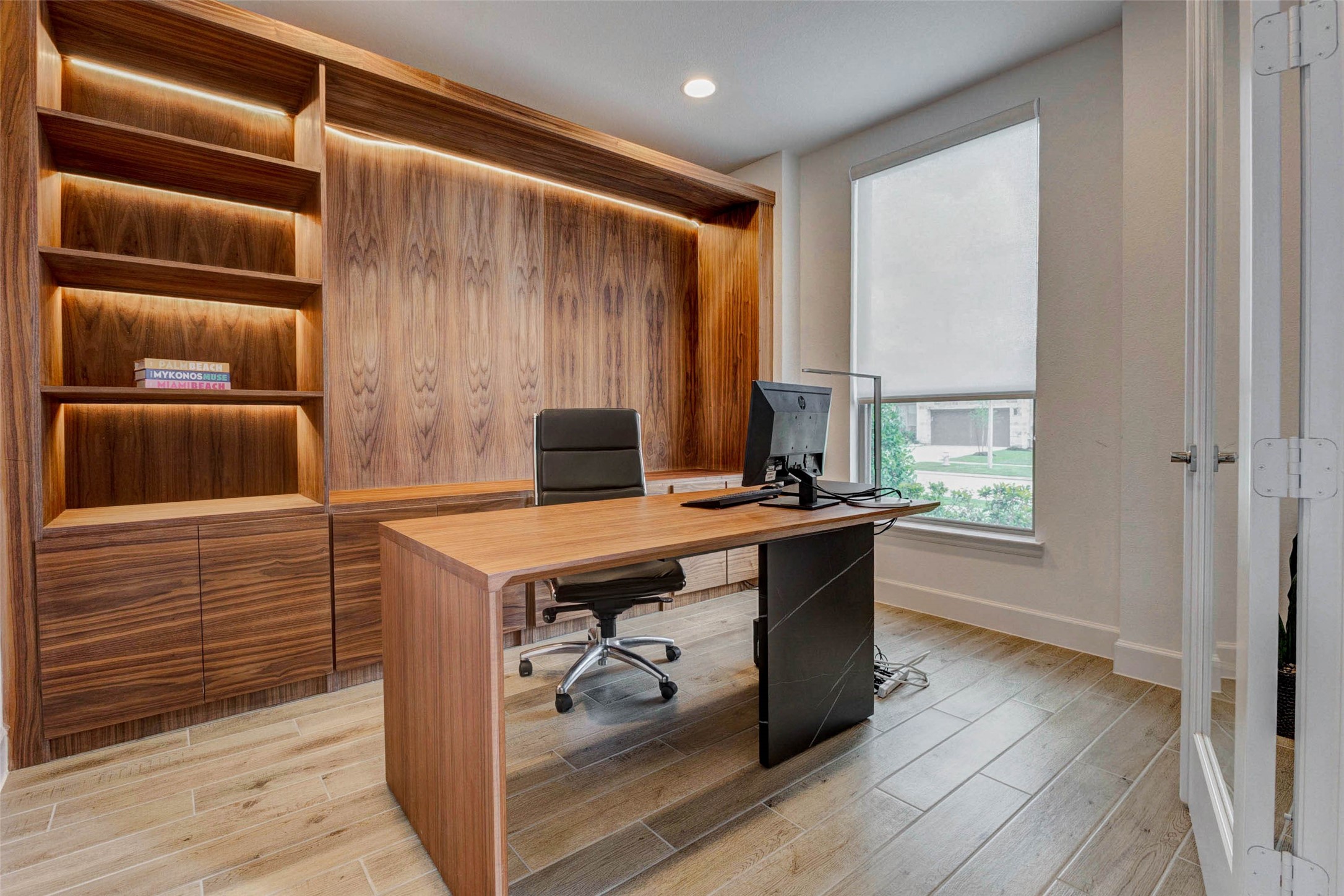 4322 Southpoint Way Fulshear, TX 77441 - Photo 6 of 50 Home office with sleek wood paneling and built-in shelving. It features a large window allowing natural light, a stylish desk, and a comfortable office chair. Ideal for a productive workspace.