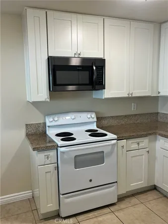 a kitchen with granite countertop white cabinets and white appliances