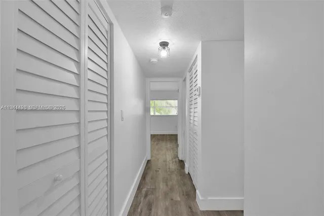 a view of a hallway with wooden floor and closet
