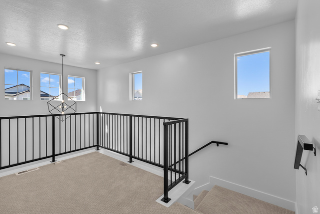 1213 West 500 South Logan, UT 84321 - Photo 10 of 29 Upper-level landing featuring a geometric chandelier, recessed lighting, carpet flooring, a black metal railing, and multiple windows