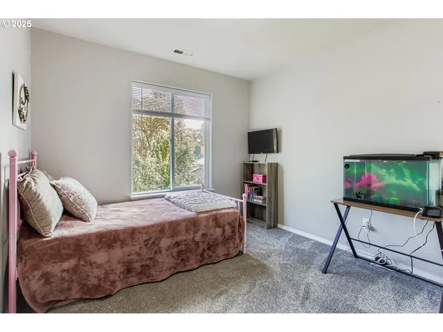 a bedroom with a bed a chair and a flat screen tv