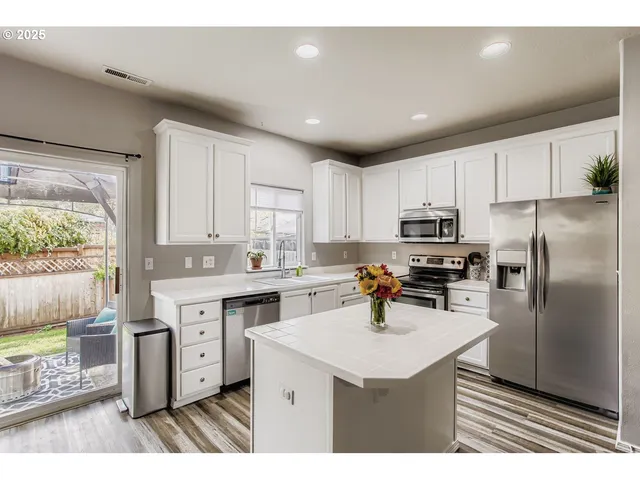 a kitchen with stainless steel appliances a sink a stove a refrigerator cabinets and a window