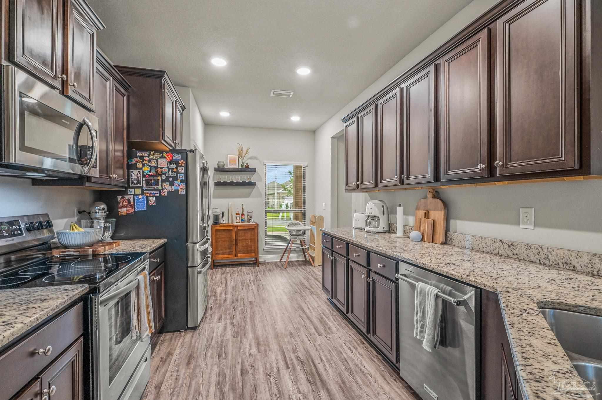 5329 Talon Road Pace, FL 32571 - Photo 13 of 45 a kitchen with stainless steel appliances granite countertop wooden cabinets a stove top oven a sink and dishwasher