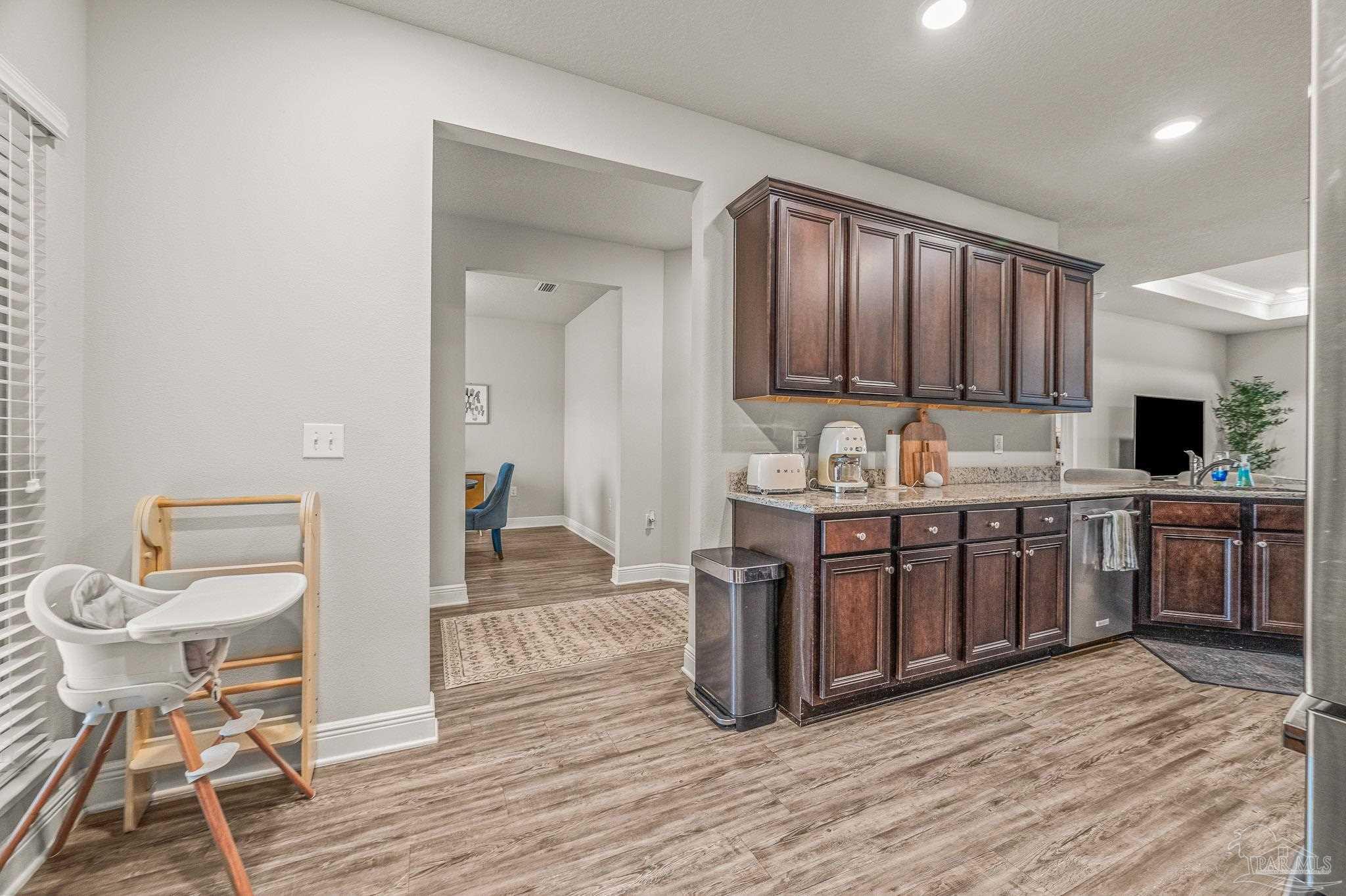 5329 Talon Road Pace, FL 32571 - Photo 10 of 45 a kitchen with stainless steel appliances granite countertop a stove a sink dishwasher a microwave oven and a dining table with wooden floor
