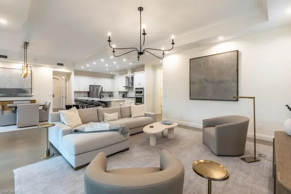 a living room with furniture kitchen view and a chandelier