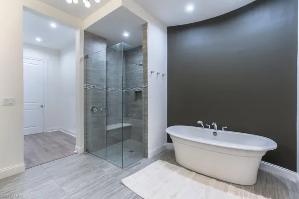 a bathroom with a white tub shower sink and mirror