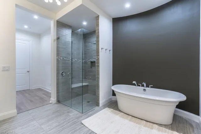 a bathroom with a white tub shower sink and mirror