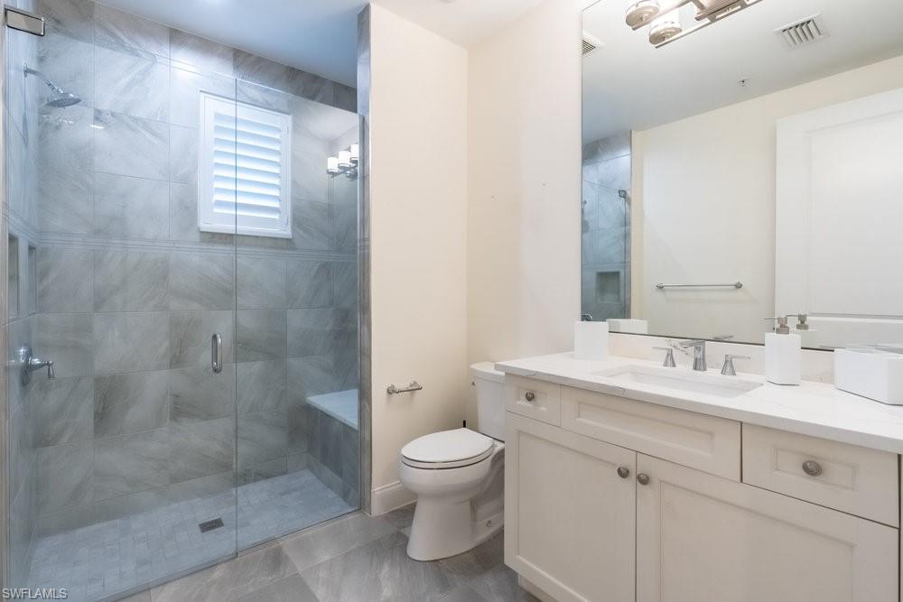 16394 Corsica Way, Unit 101 Naples, FL 34110 - Photo 24 of 43 a bathroom with a double vanity sink toilet and shower