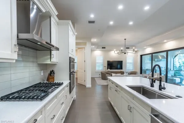 a large kitchen with stainless steel appliances a sink a stove and cabinets