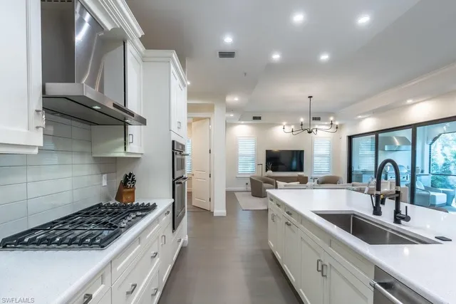 a large kitchen with stainless steel appliances a sink a stove and cabinets