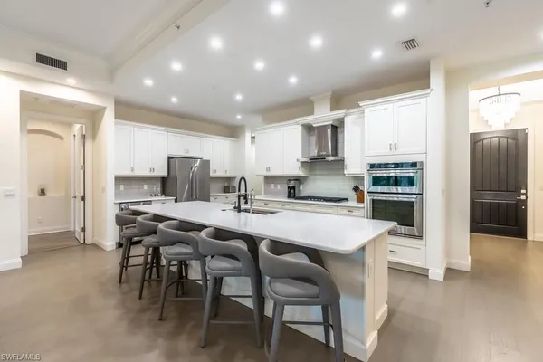 a kitchen with stainless steel appliances a table chairs refrigerator and cabinets