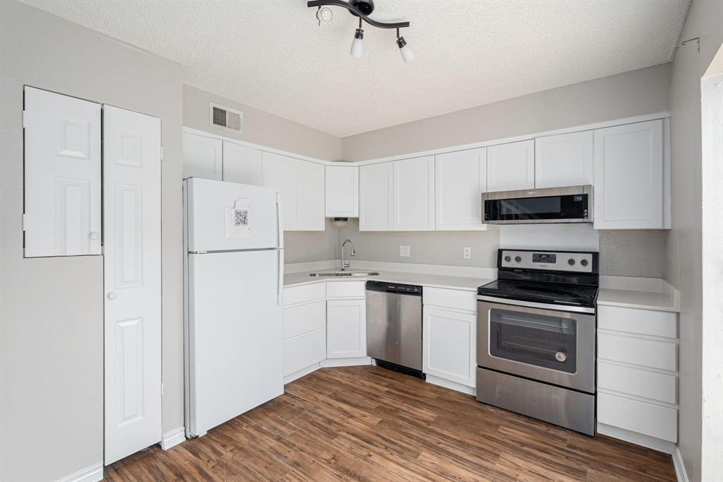 900 South Tennessee Street, Unit 13 McKinney, TX 75069 - Photo 6 of 16 a kitchen with granite countertop a refrigerator stove and white cabinets