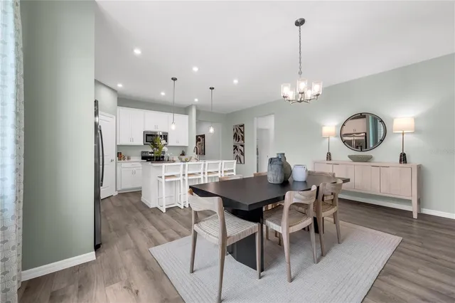a view of a dining room and livingroom with furniture wooden floor a chandelier