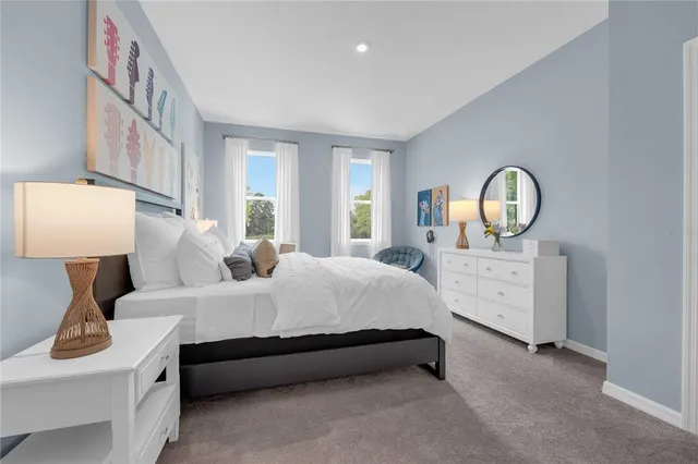 a spacious bedroom with a bed a mirror on dresser and a window