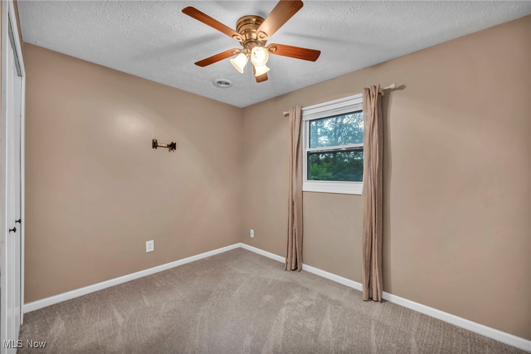 47655 Cooper Foster Park Road Amherst, OH 44001 - Photo 15 of 49 Carpeted empty room featuring a textured ceiling and ceiling fan