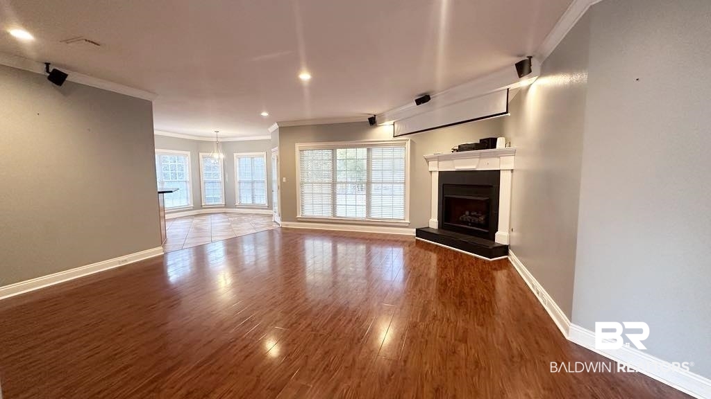 23289 McPhillips Road Loxley, AL 36551 - Photo 3 of 19 Spacious living area featuring wood-finish flooring, a fireplace with a white mantel, and multiple windows