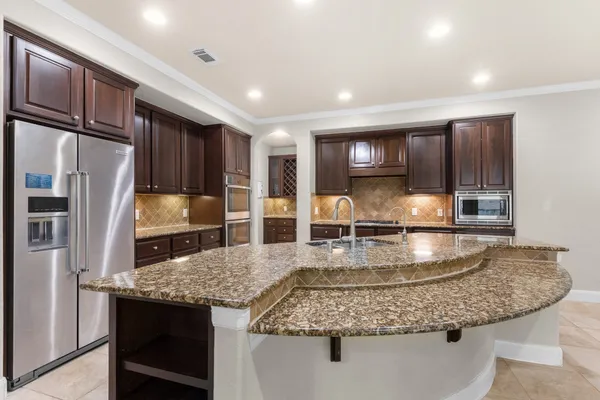 a view of a kitchen with stainless steel appliances granite countertop a stove and a refrigerator