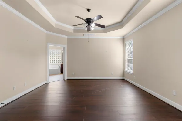 a view of an empty room with wooden floor and a ceiling fan