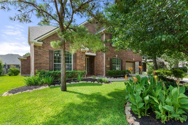 a front view of a house with a yard and large tree