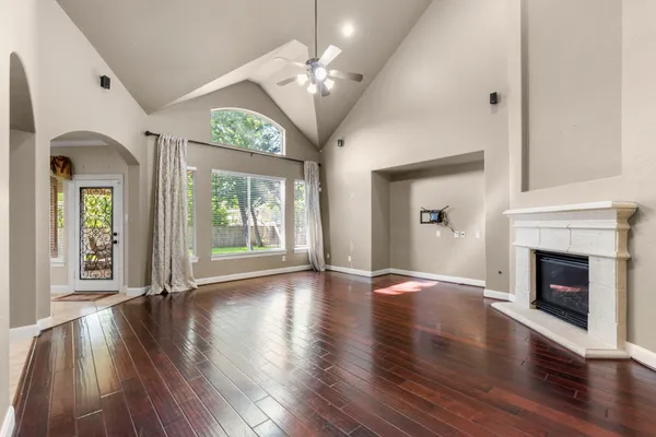 a view of an empty room with wooden floor fireplace and a window