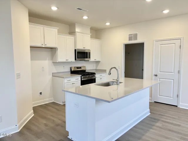 a kitchen with kitchen island white cabinets and refrigerator