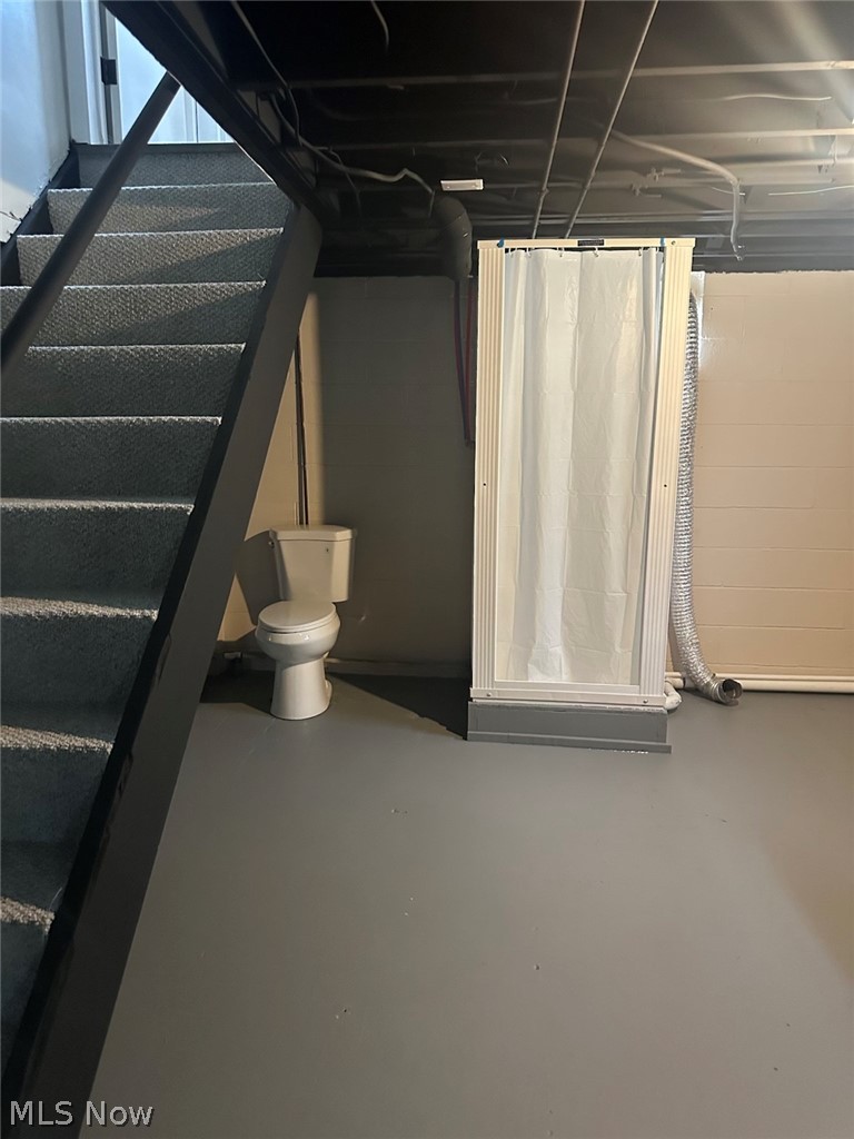 628 Creed Street Struthers, OH 44471 - Photo 19 of 20 Finished basement space featuring a white toilet, enclosed shower with white curtain, and a metal staircase with textured treads