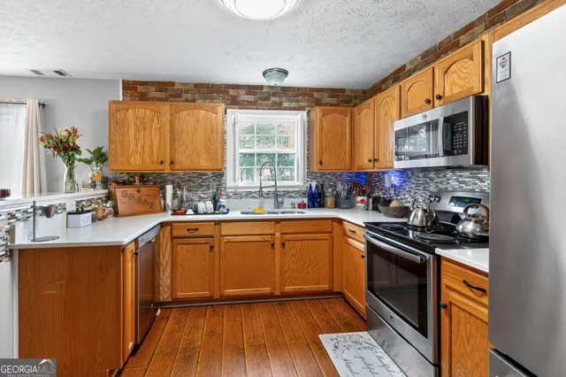 a kitchen with stainless steel appliances granite countertop wooden cabinets stove top oven and sink