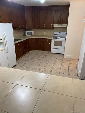 a kitchen with granite countertop a stove a sink and a refrigerator