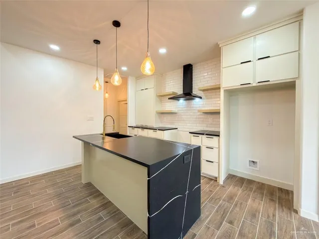 a kitchen with kitchen island granite countertop a sink appliances and cabinets